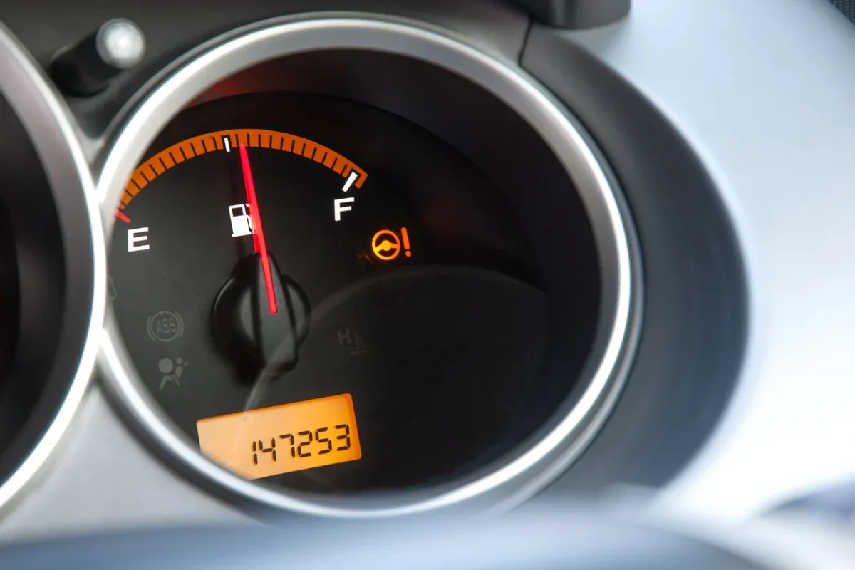 Close-up of a car instrument cluster showing a fuel gauge and a digital odometer reading 147,253 miles