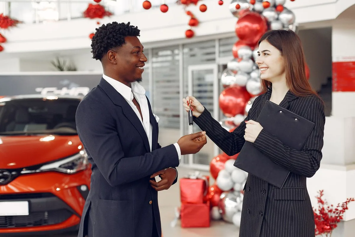 A happy buyer receiving car keys after an approved in-house financing deal at a dealership