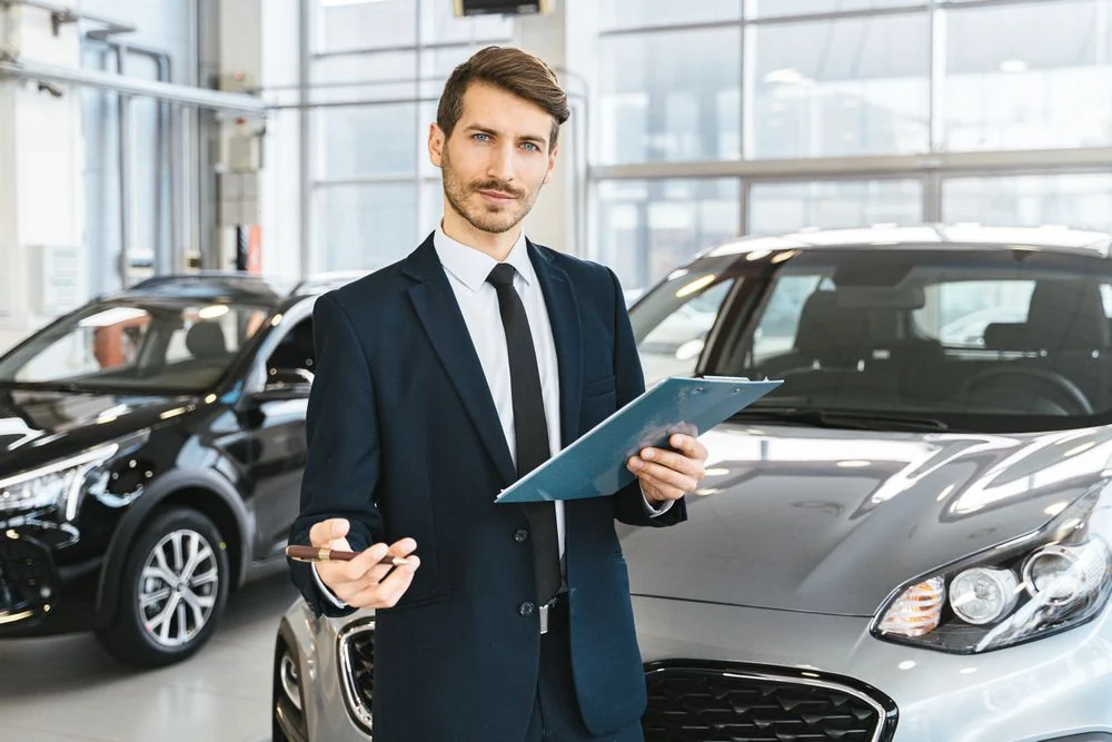 A dealership finance manager on the showroom floor, ready to help a first-time buyer with no credit get approved
