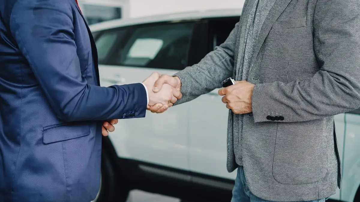 Customer and finance manager shaking hands on an in-house car loan at an Oklahoma dealership